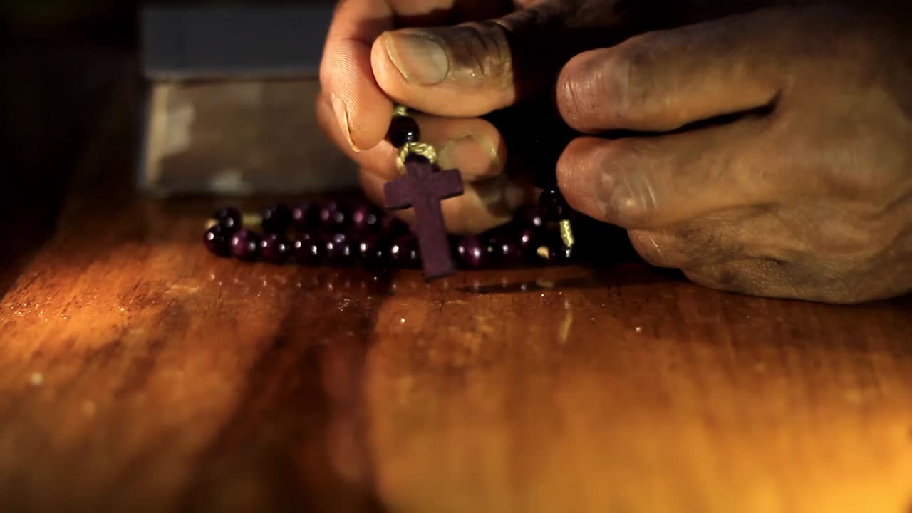 rezando a dios con las manos junto con la biblia y el hombre cruzado del caribe rezando con fondo negro almacen de video