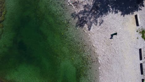 toma aérea de arriba hacia abajo de agua clara con puente en idrijska bela durante un día soleado en eslovenia - toma ascendente