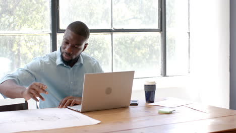 working in office, man using laptop and reviewing documents at desk