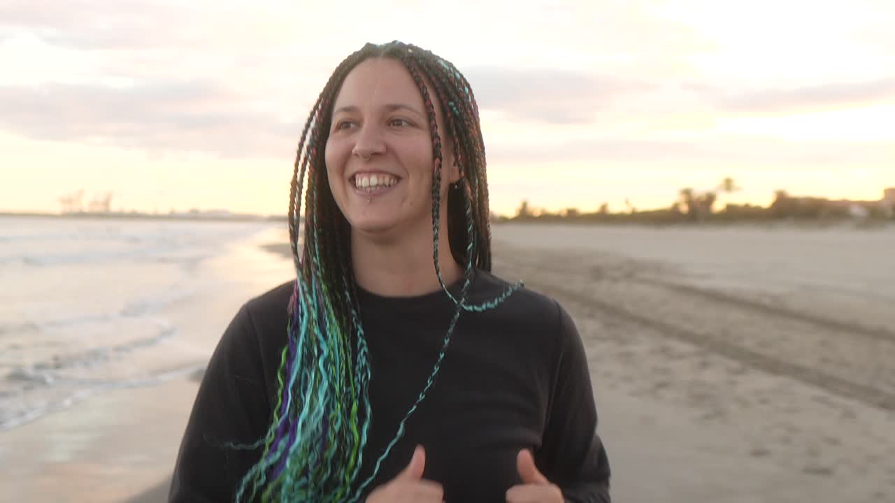mujer con trenzas corriendo por la playa con una sonrisa