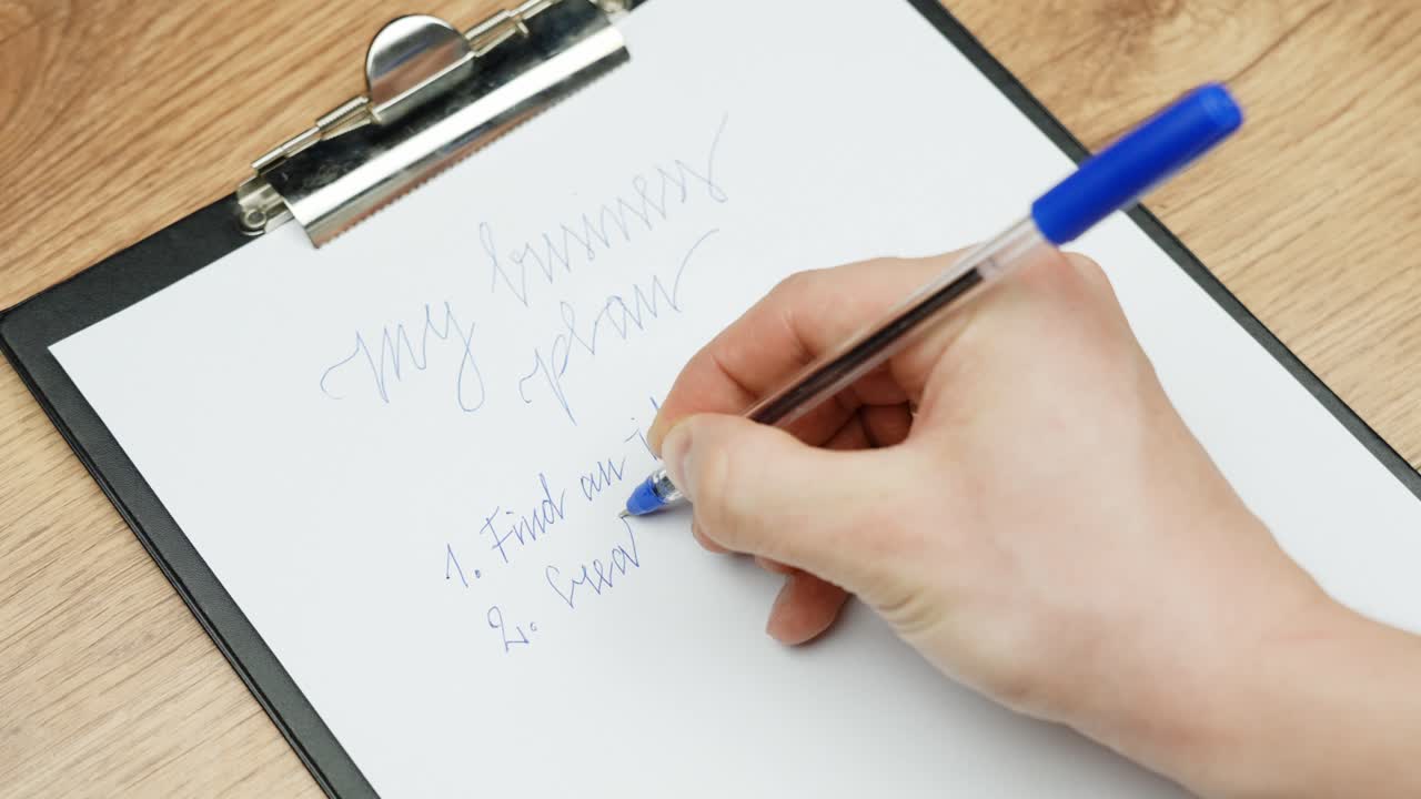 Close-Up of hands writing a business plan with a blue pen on paper.