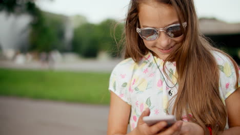 close-up view of joyful girl chatting on smartphone outside.