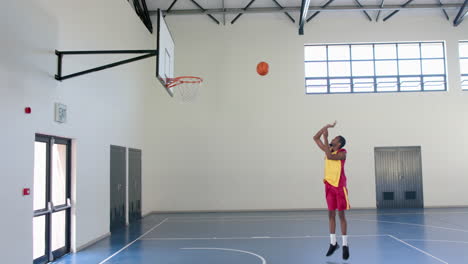 a basketball player shoots for the hoop in an indoor court