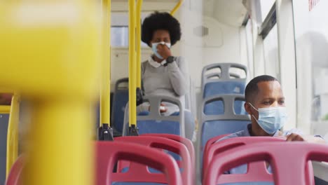 african american man and woman with face masks sitting in bus