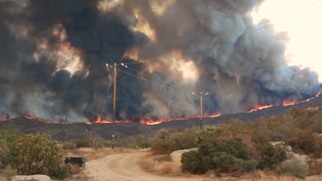 Panorama-Shot-of-burning-wildfire-with-dark-smoke-in-California-during-high-temperatures-in-climate-change---water-bomber-plane-flying-around