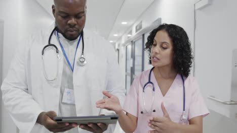 Busy-diverse-doctors-using-tablet-and-talking-in-hospital-in-slow-motion