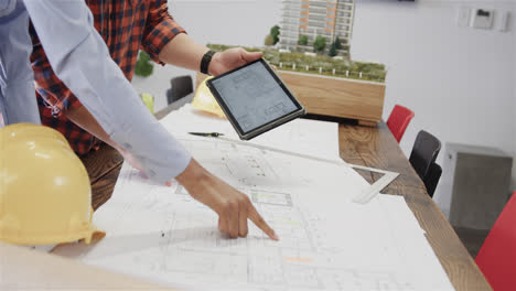 Midsection-of-diverse-male-and-female-architects-with-tablet-discussing-blueprints,-slow-motion