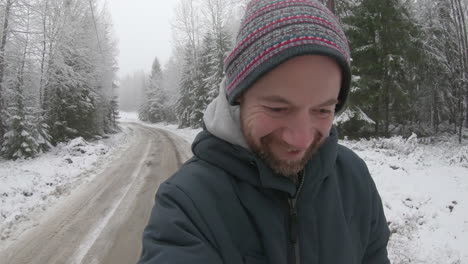 an ecstatically happy man in his 30s walks along a snowy road in the countryside