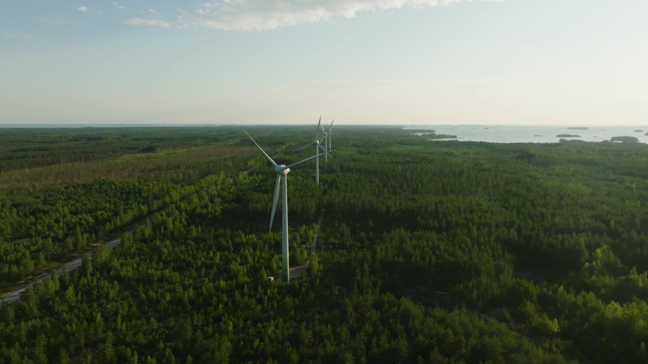 Aerial tracking shot of Sustainable energy: Wind power power generators standing in Hanko