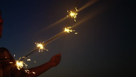 couple playing with sparklers on beach at dusk 4k