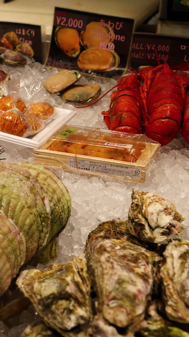 Close-up panning shot of king crab legs, sea urchin, and prawns on crushed ice