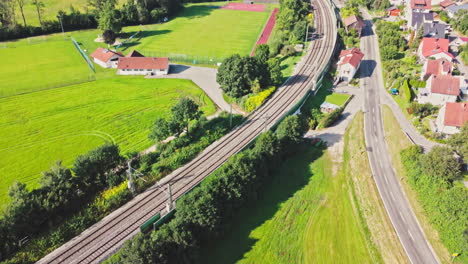 Drohnenaufnahme,-Die-Von-Bahngleisen-Abfährt-Und-Ein-Kleines-Dorf-In-Süddeutschland-Freigibt