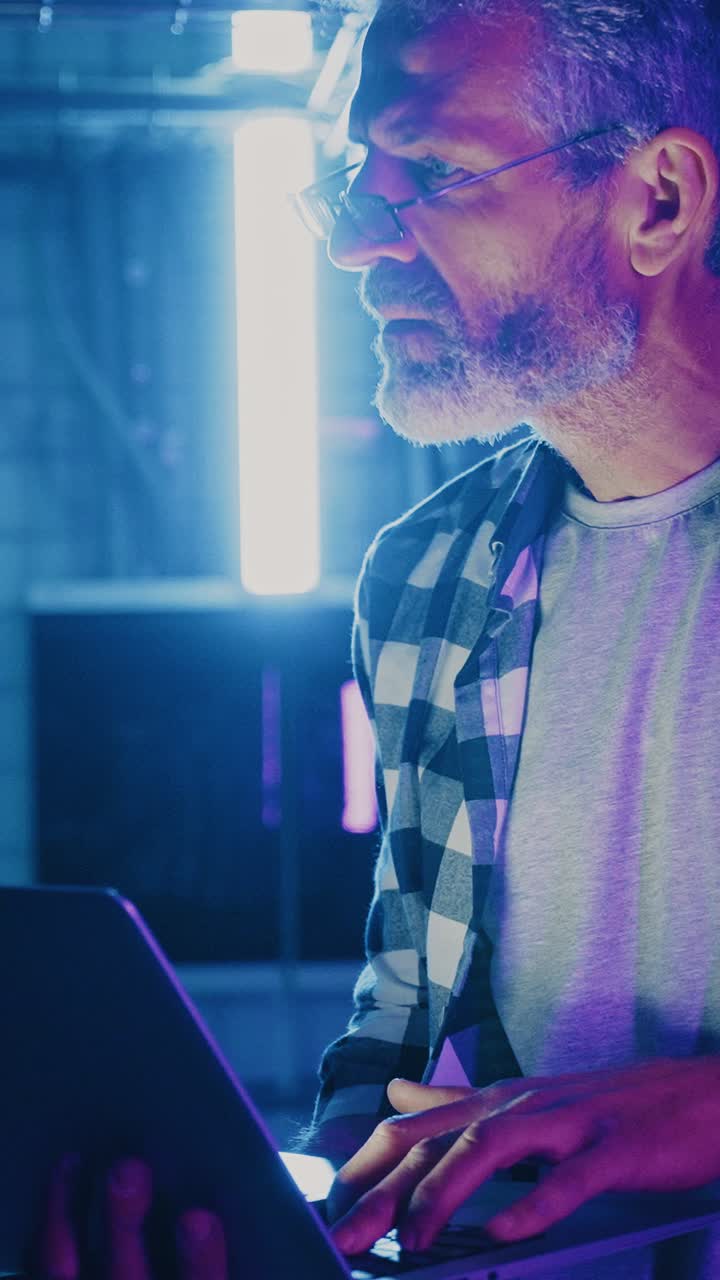 Focused Man Working on Laptop in a Neon Lit Room