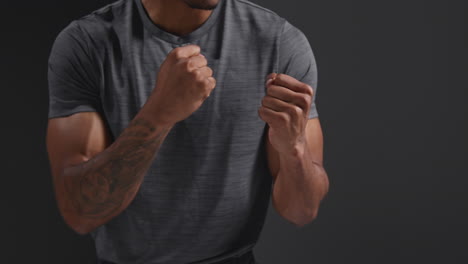 fotografía de estudio de cerca de un boxeador con los puños cerrados entrenando en el gimnasio preparándose para luchar contra un fondo negro