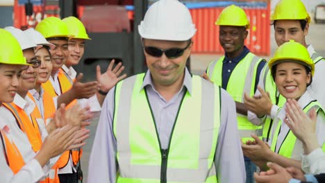 diverse group of container workers standing in line clapping hand congratulations to the successful supervisors in import and export business logistic company. foreman shaking hands with manager