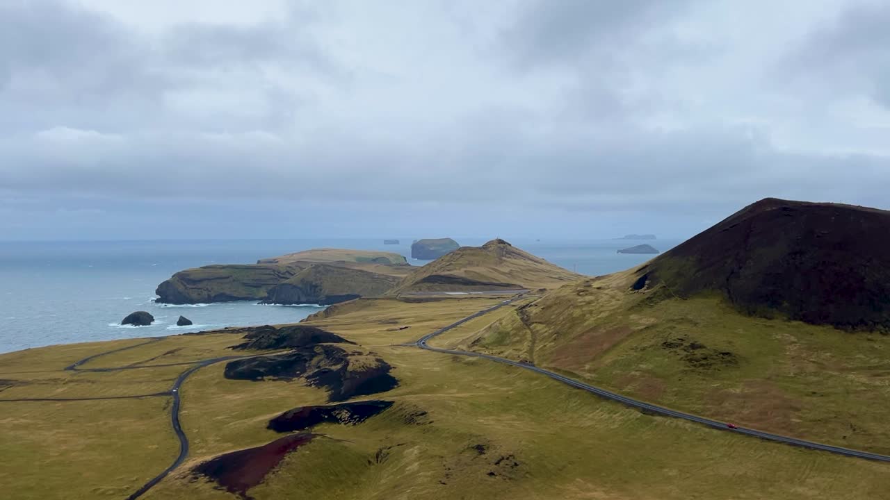 Helgafell volcano and Icelandic coastline under cloudy skies, remote and rugged, aerial view