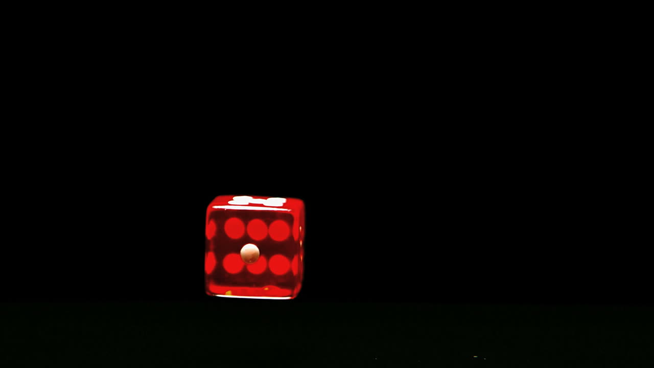 Red dice falling and bouncing close up on black background