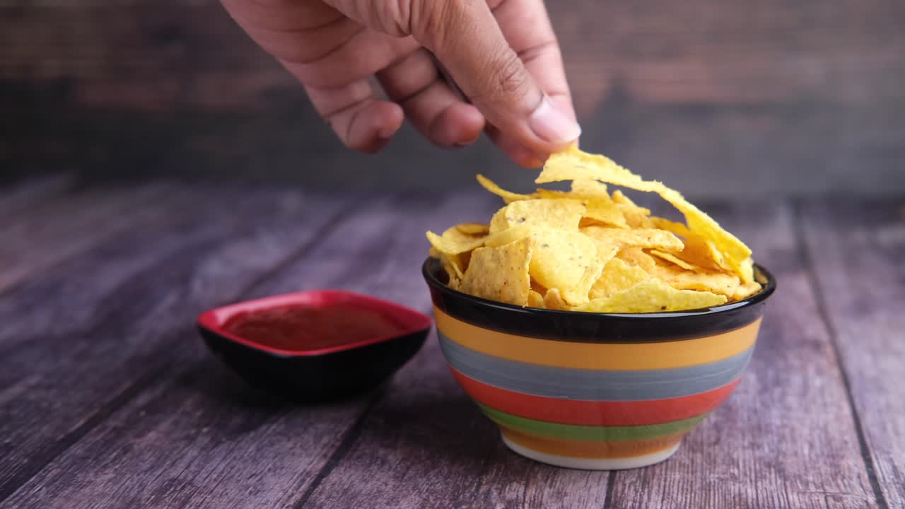 Mano che prende chips di tortilla da una ciotola