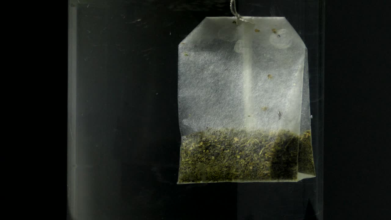 Close-up of a tea bag steeping in a glass of water