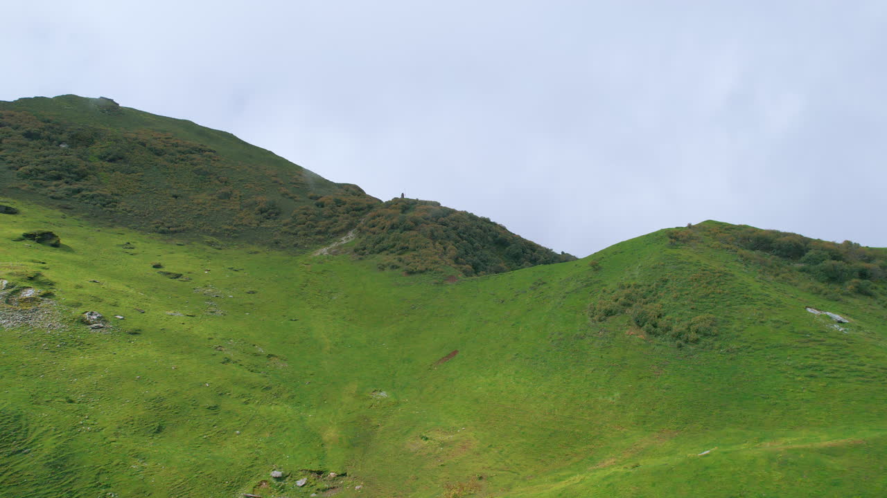 양들의 그룹은 언덕 위의 예수 그리스도의 십자가 구조를 중심으로 달리며, 네팔의 풍경