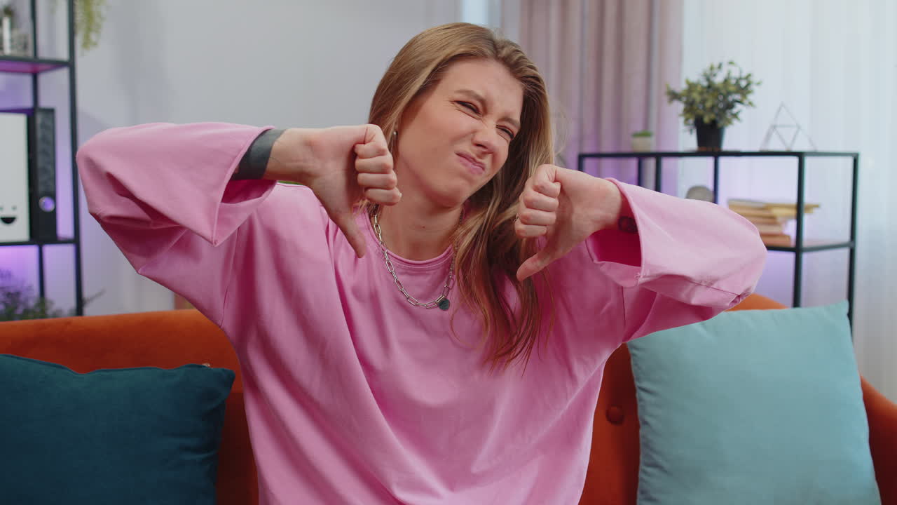 mujer joven molesta mostrando pulgares hacia abajo, no le gusta el mal trabajo, desaprobación, retroalimentación insatisfecha en casa