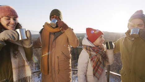 friends toasting with hot drinks in snowy mountains