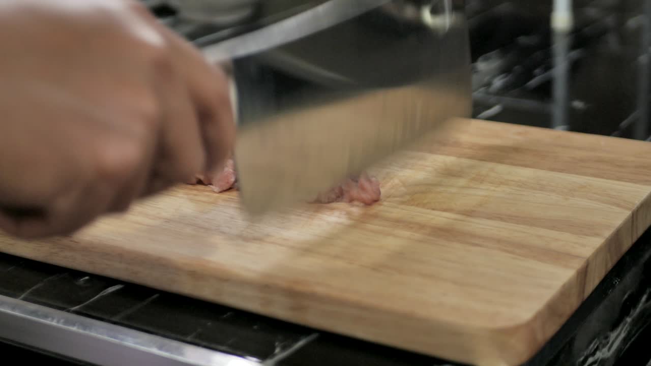 부에서 누군가 절단판에 돼지고기를 고 있습니다. 이 클립은 4k와 현실적인 빛으로 촬영되었습니다.