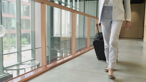 an unrecognizable businesswoman walks backwards with a trolley. she is on his way to an important business trip. we follow her.