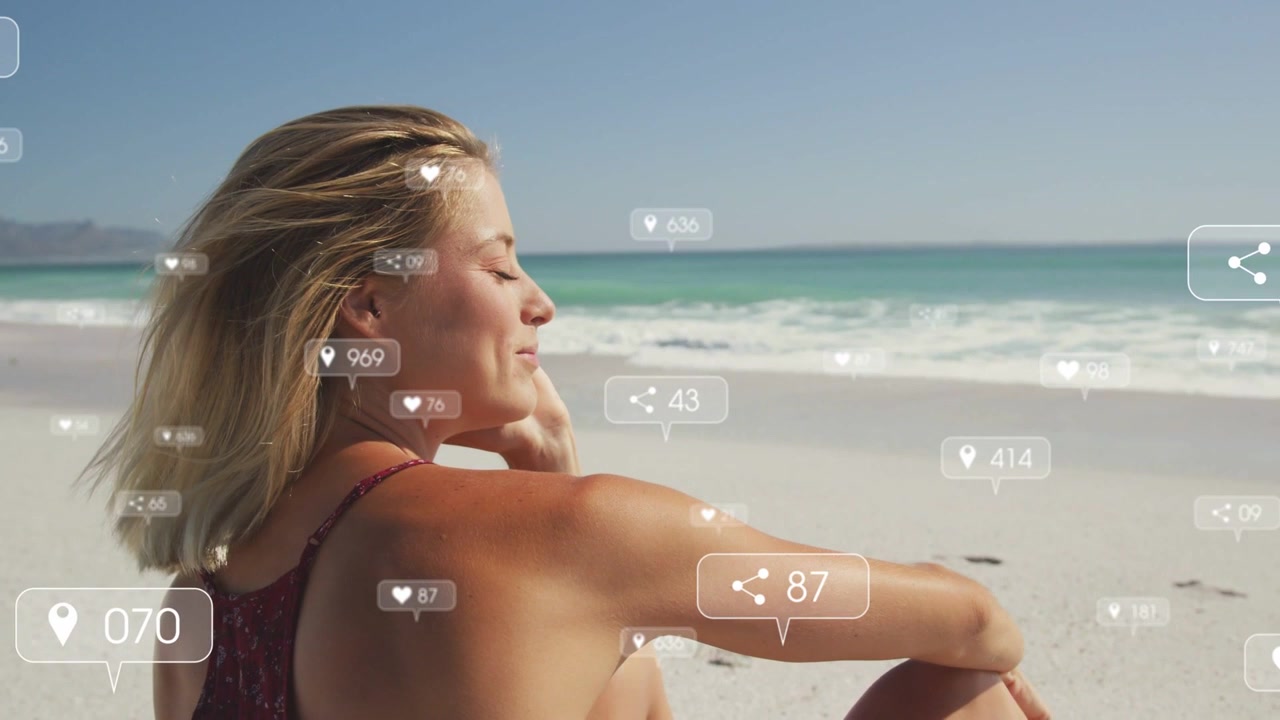 Donna seduta in spiaggia, la telecamera esegue una panoramica creando un'interfaccia utente social intorno a lei che mostra dei "mi piace" mentre si ripara gli occhi dal sole.