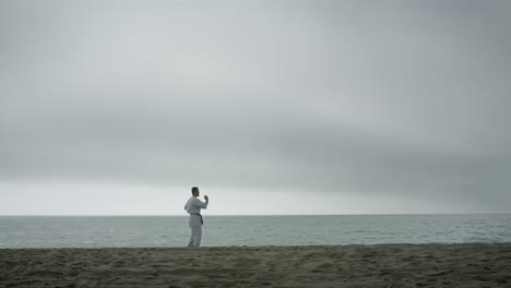 Luchador-Entrenando-Artes-Marciales-En-La-Playa.-Hombre-De-Karate-Practicando-Técnica-De-Combate