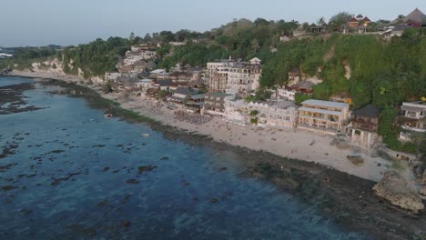 Panning-Drone-shot-of-Bingin-Beach-buildings-at-sunset-and-low-tide-in-Uluwatu-Bali-Indonesia