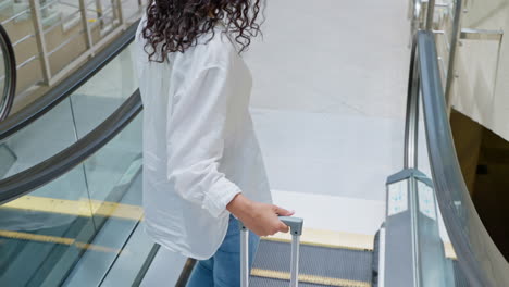 mujer en escalera mecánica con maleta