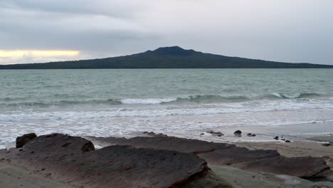 Hermosa-Isla-De-Rangitoto,-Un-Volcán-Inactivo-Visible-Desde-Una-Playa-Rocosa-En-El-Norte-De-Auckland,-Nueva-Zelanda