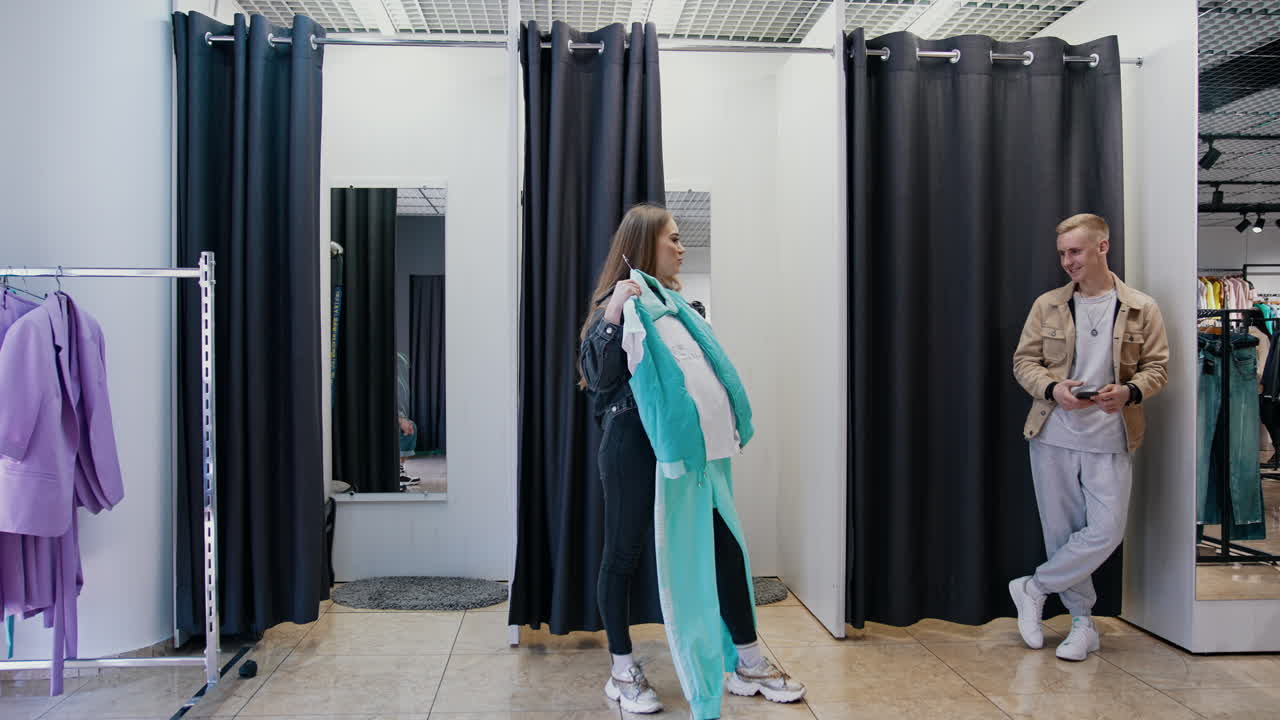 Girl trying clothes in fashion store. Young woman trying clothes in fitting room