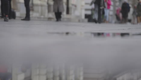 people walking on a city street with reflection in a puddle