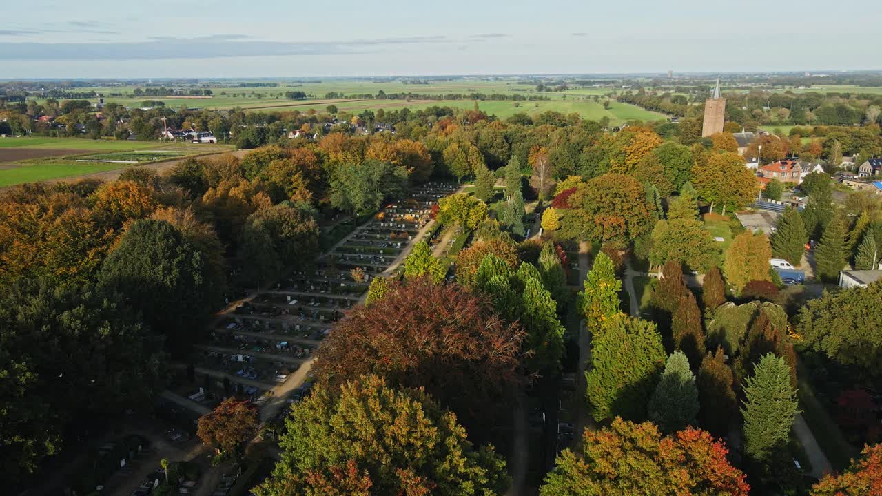 Stunning jib up of a peaceful graveyard surround by trees in a beautiful small town on a sunny autumn day