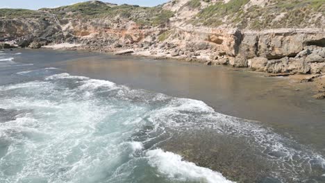 Rocky-sea-coastline-with-waves-and-people-on-holidays-at-the-beach