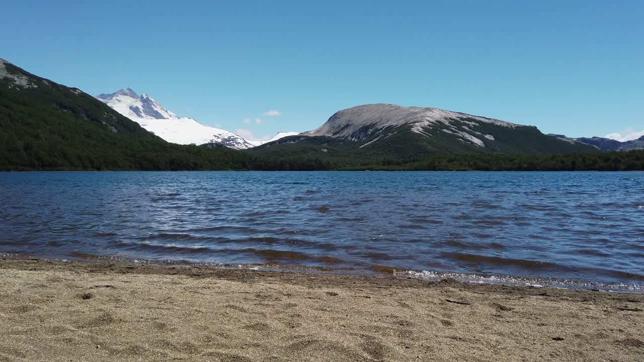 Grov sandstrand, dybblåt vand og klar bjergluft i Laguna Ilon, Bariloche