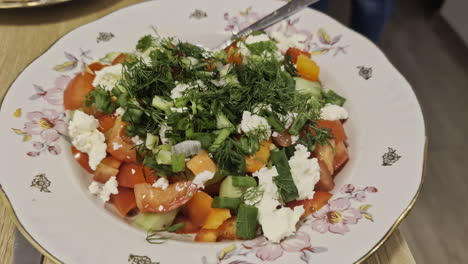 Ensalada-Griega-De-Cerca-En-Plato-Floral,-Pepino,-Tomate,-Queso-Feta-Y-Pimienta.