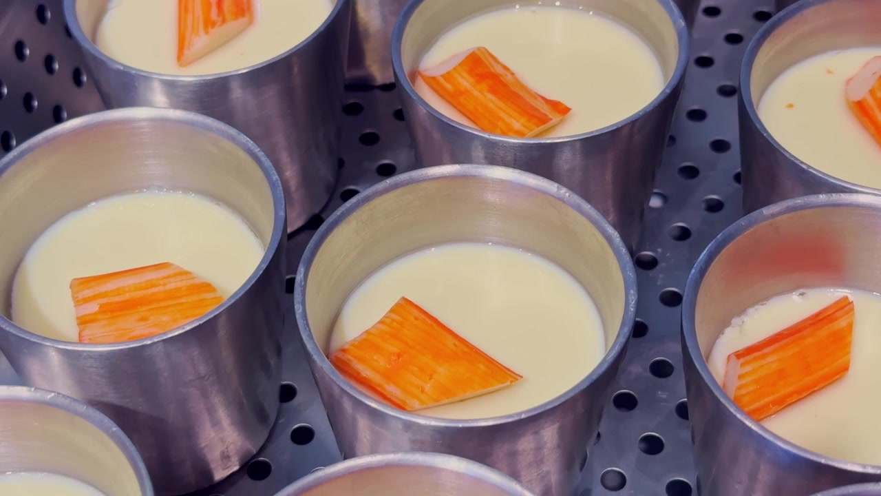 Close-up de creme de ovo cozido no vapor sedoso coberto com fatias de kani-kama, criando um prato delicado e saboroso de estilo asiático com textura macia