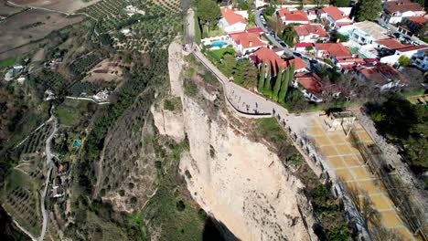 An-aerial-tilt-down-reveals-the-magnificent-houses-by-the-cliffs-of-Ronda,-Spain