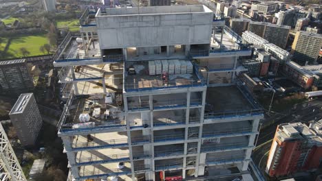 4K-60FPS-Aerial-drone-flight-around-a-new-tower-building-under-construction,-revealing-the-bare-concrete-structure-and-people-working-on-the-rooftop