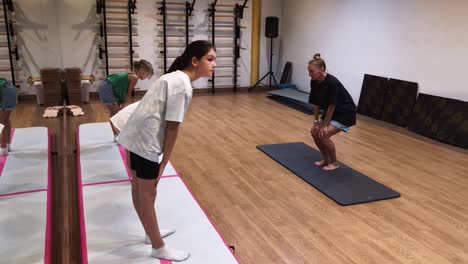 children and women doing yoga exercises in a gym