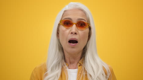 outraged old woman shouting inside. shocked lady opening mouth in studio.