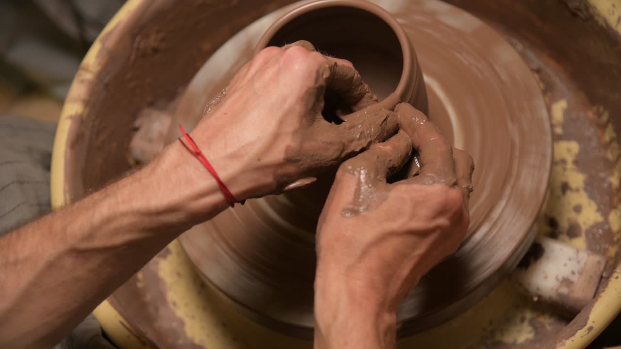 Primo piano di mani maschili che creano una ciotola di argilla su un tornio da vasaio. Artigianato e produzione di esclusive stoviglie da tè in argilla