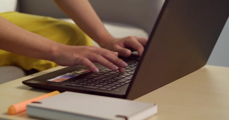 En person, der hurtigt taster på en bærbar computer på en hyggelig arbejdsplads, der viser produktivitet og teknologisk engagement.