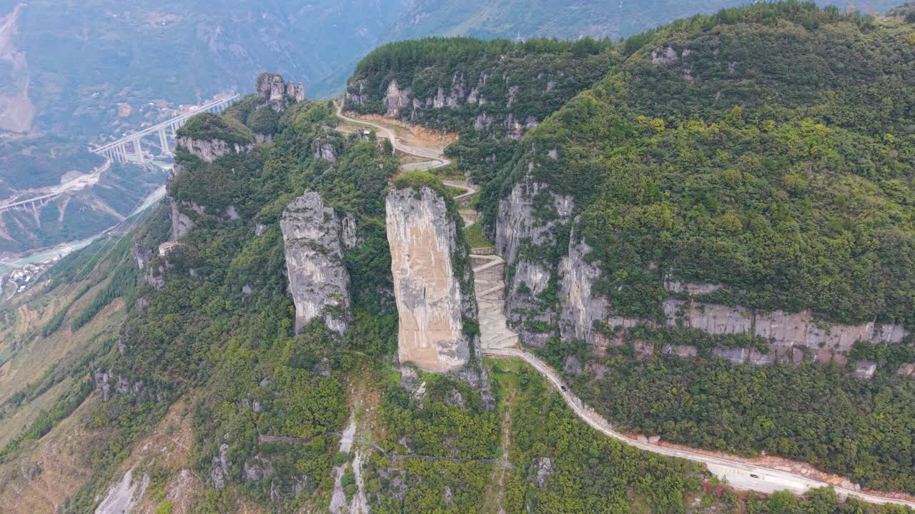 Aerial view of the steep, sheer rock formations and the zigzag road carved into the cliffside at Lingpaishi, Wuxi County, China. Captures remote natural beauty and engineering. UHD