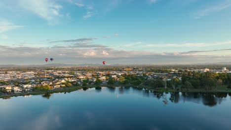 hot air balloons rising and heading over hamilton city