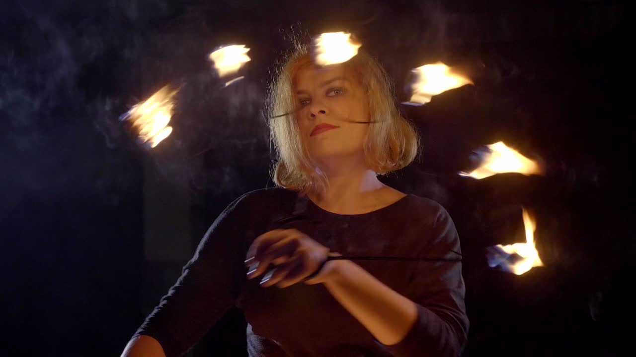 una artista de yong hace un espectáculo de fuego en la oscuridad a cámara lenta.