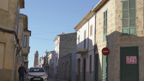 narrow street in a spanish town with cars and people